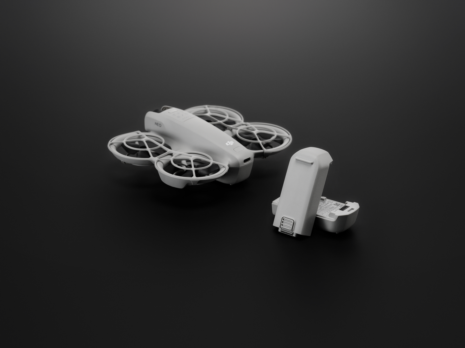 Drone e batteria staccata su una superficie nera.