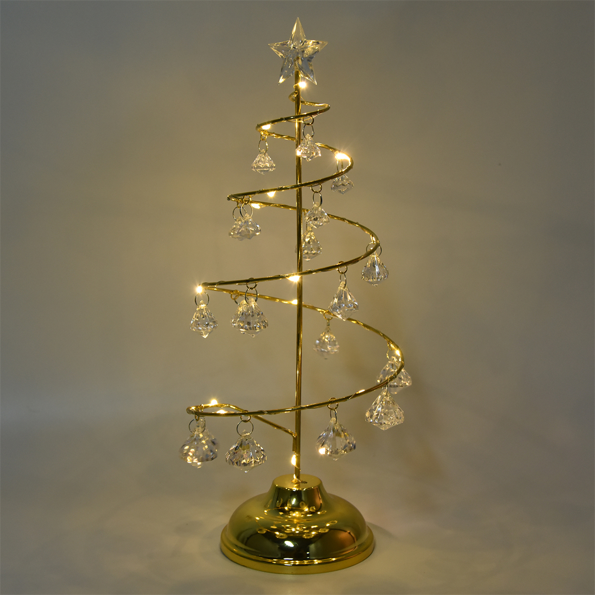 Ein goldfarbener Weihnachtsbaum mit hängenden Kristallornamenten, beleuchtet mit Lichtern auf einem goldenen Sockel.