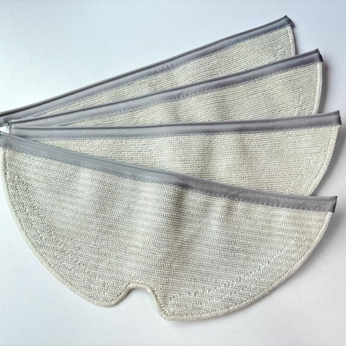 Cztery biało-szare nakładki do mopa ułożone w kształt wachlarza na białym tle. Szara obwódka.