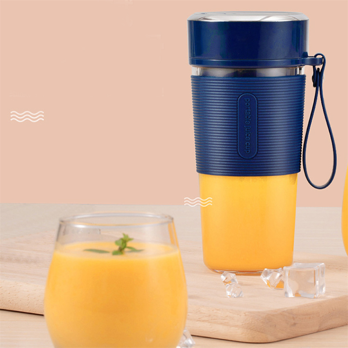 Tragbarer Saftbecher, voll mit Orangensaft, neben einem Glas Saft und Eiswürfeln.