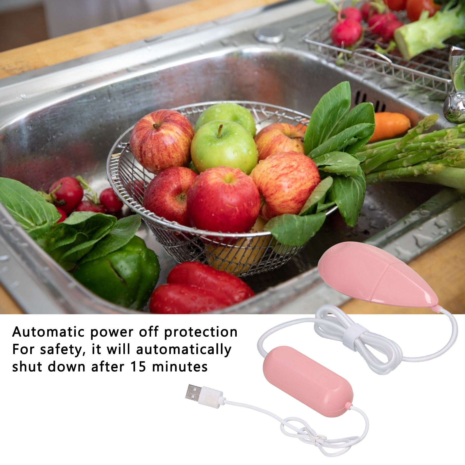 Ein Metallkorb mit Äpfeln und Gemüse in einem Waschbecken, mit rosa Reinigungsgeräten und einem USB-Kabel.