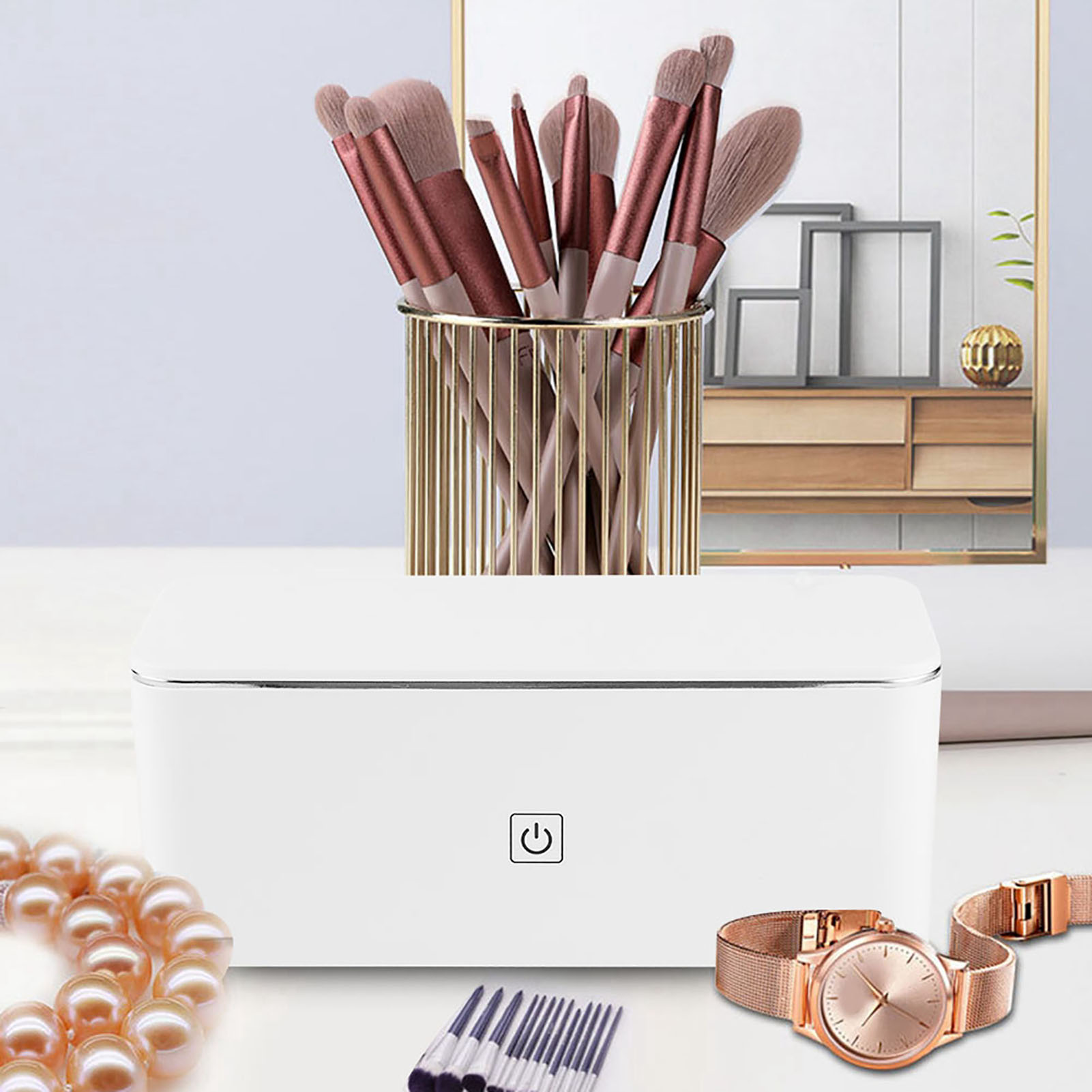 Weiße Box mit Make-up-Pinseln, Schmuck und einer Uhr. Ein Spiegel ist im Hintergrund.