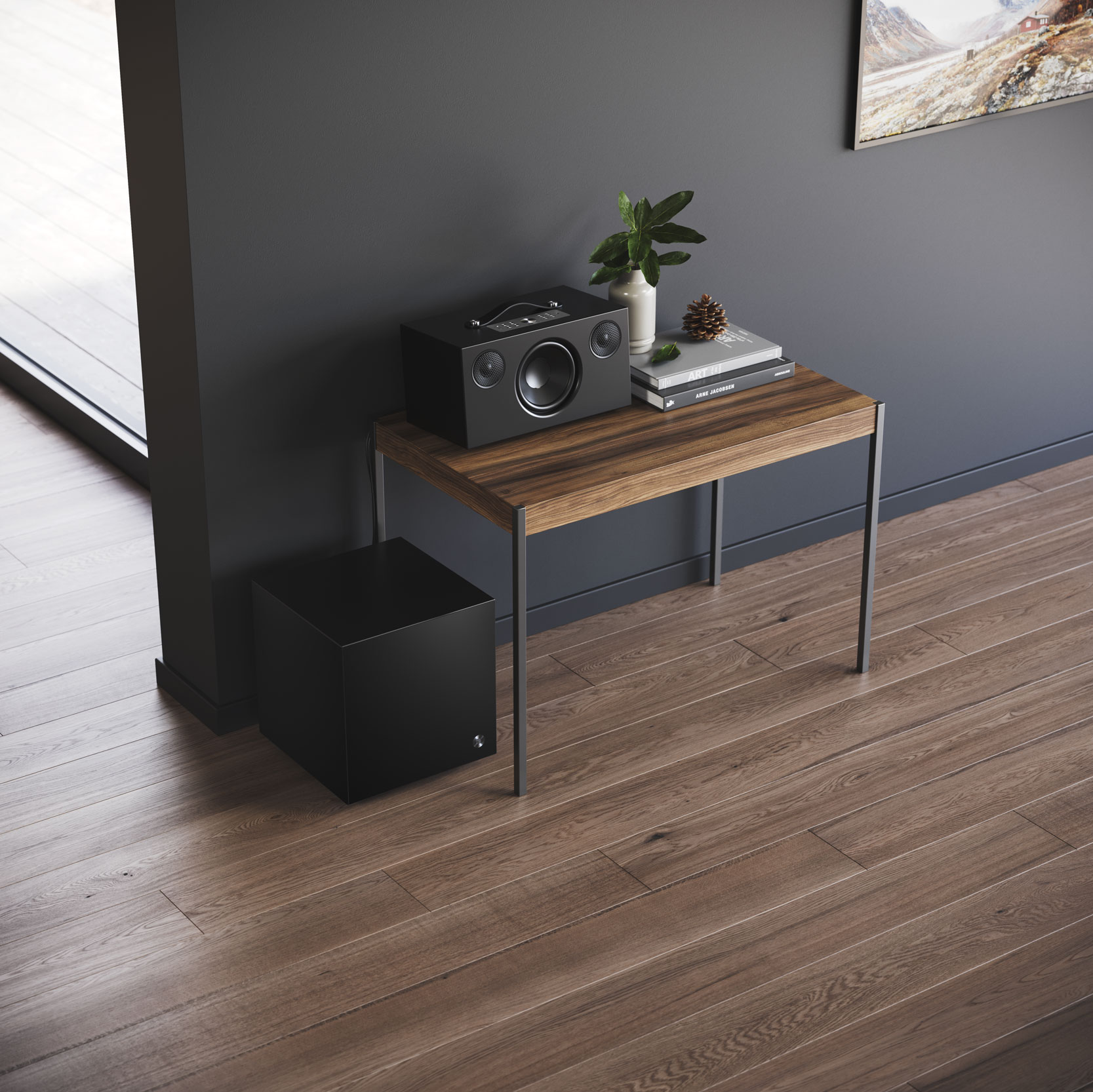 A black speaker on a brown table next to a smaller black subwoofer, with a dark wall behind.