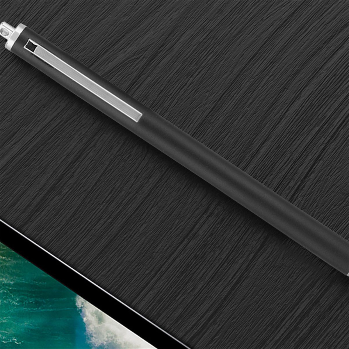 Schwarzer Stift auf strukturiertem dunklem Hintergrund, nahe einer Tablet-Kante.
