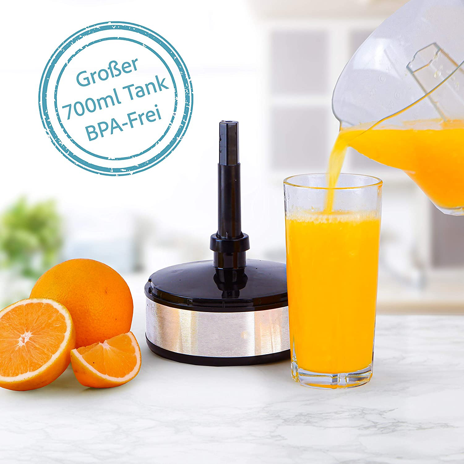 Orangensaft wird in ein Glas gegossen. Orangen liegen daneben, die Saftpresse im Hintergrund.