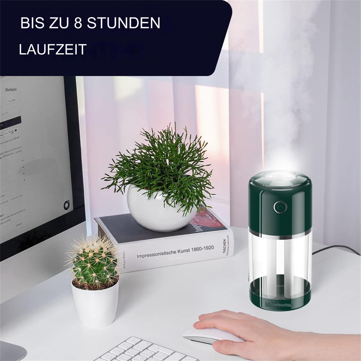 Ein grüner und weißer Luftbefeuchter mit einer Pflanze, einem Buch, einem Kaktus und einem Computer auf einem weißen Schreibtisch.