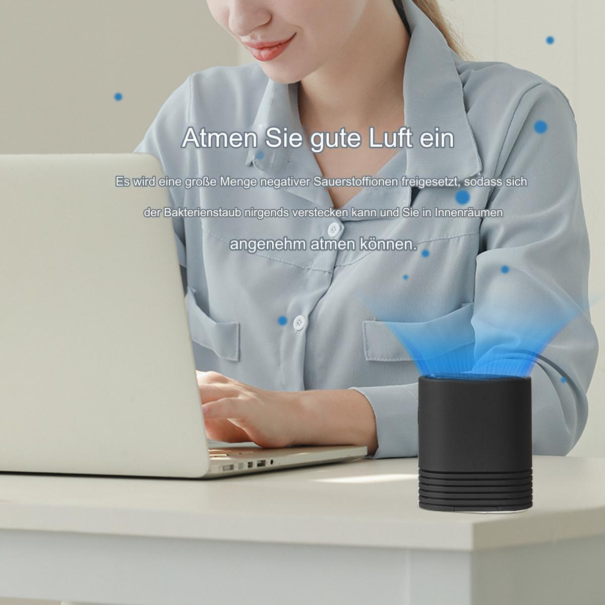 Frau benutzt Laptop neben schwarzem Luftreiniger, blaue Luftpartikel sichtbar.