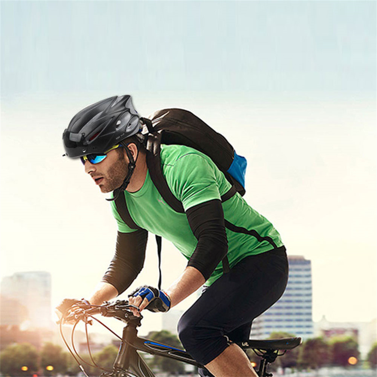 Radfahrer fährt Fahrrad, trägt Helm, Sonnenbrille und grünes Hemd.