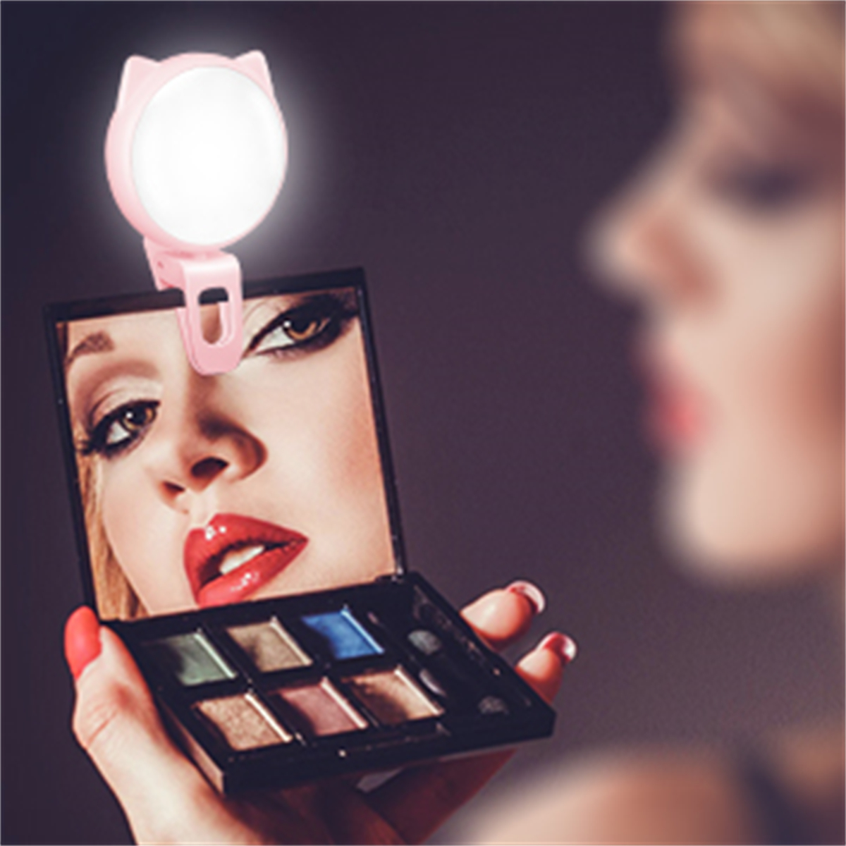 Reflexion einer Frau in einem Kompaktspiegel, beleuchtet von einem rosa Katzenohrlicht, mit Make-up.