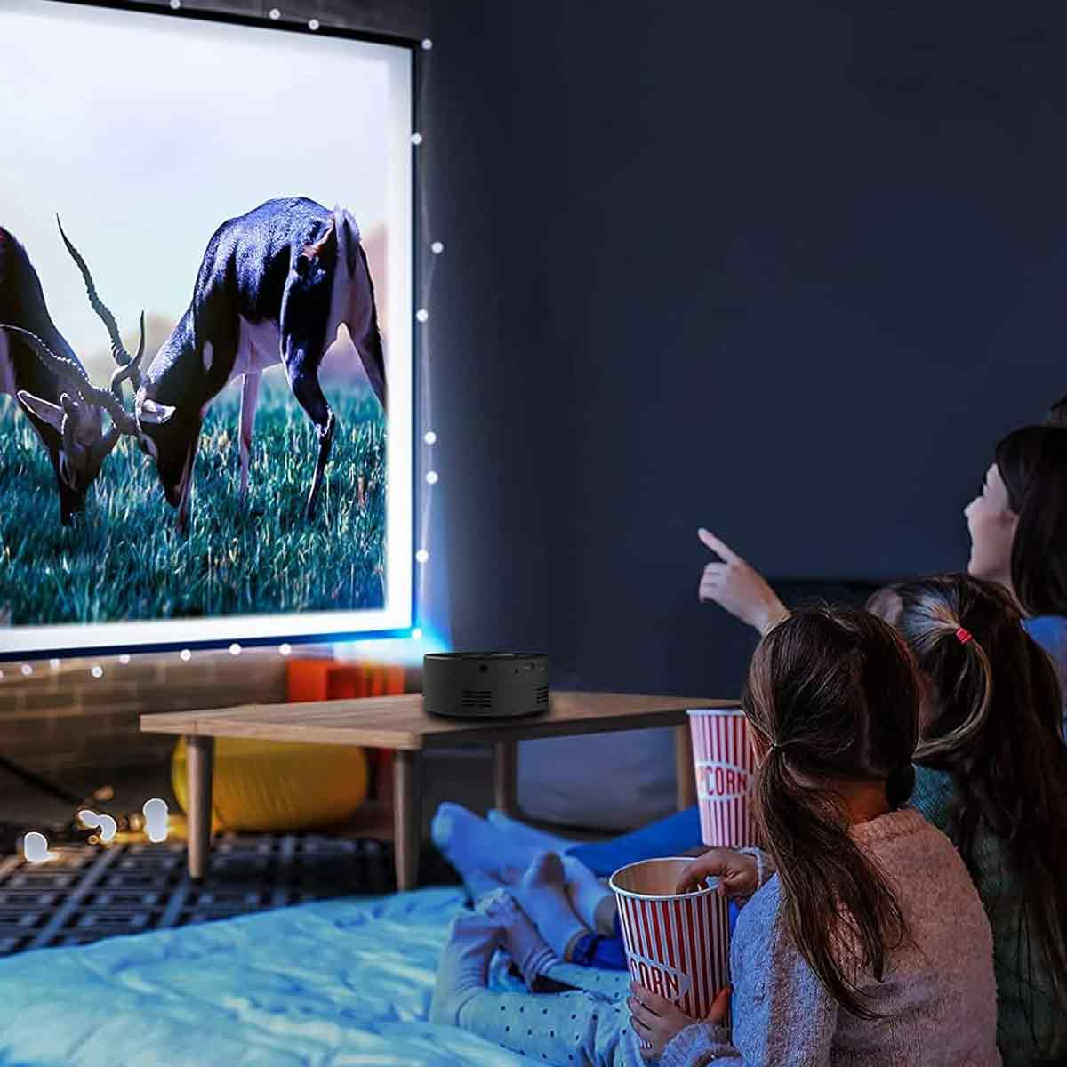 Menschen, die einen Bildschirm betrachten, der ein Video zeigt, mit Popcorn-Eimern auf einem Tisch.