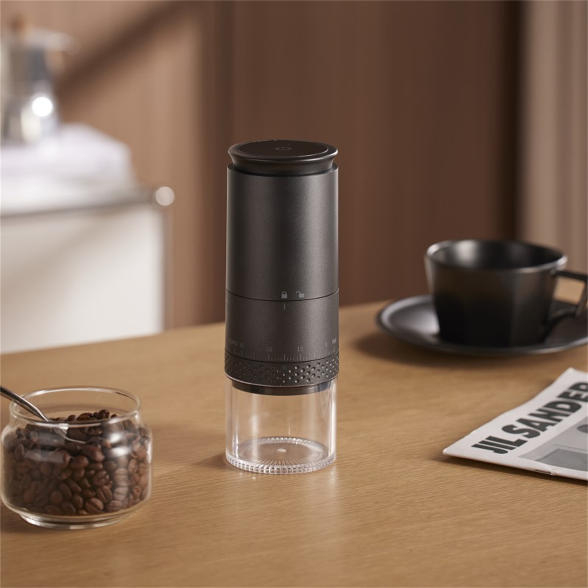 Eine schwarze Kaffeemühle mit transparentem Boden und ein Glas Kaffeebohnen.