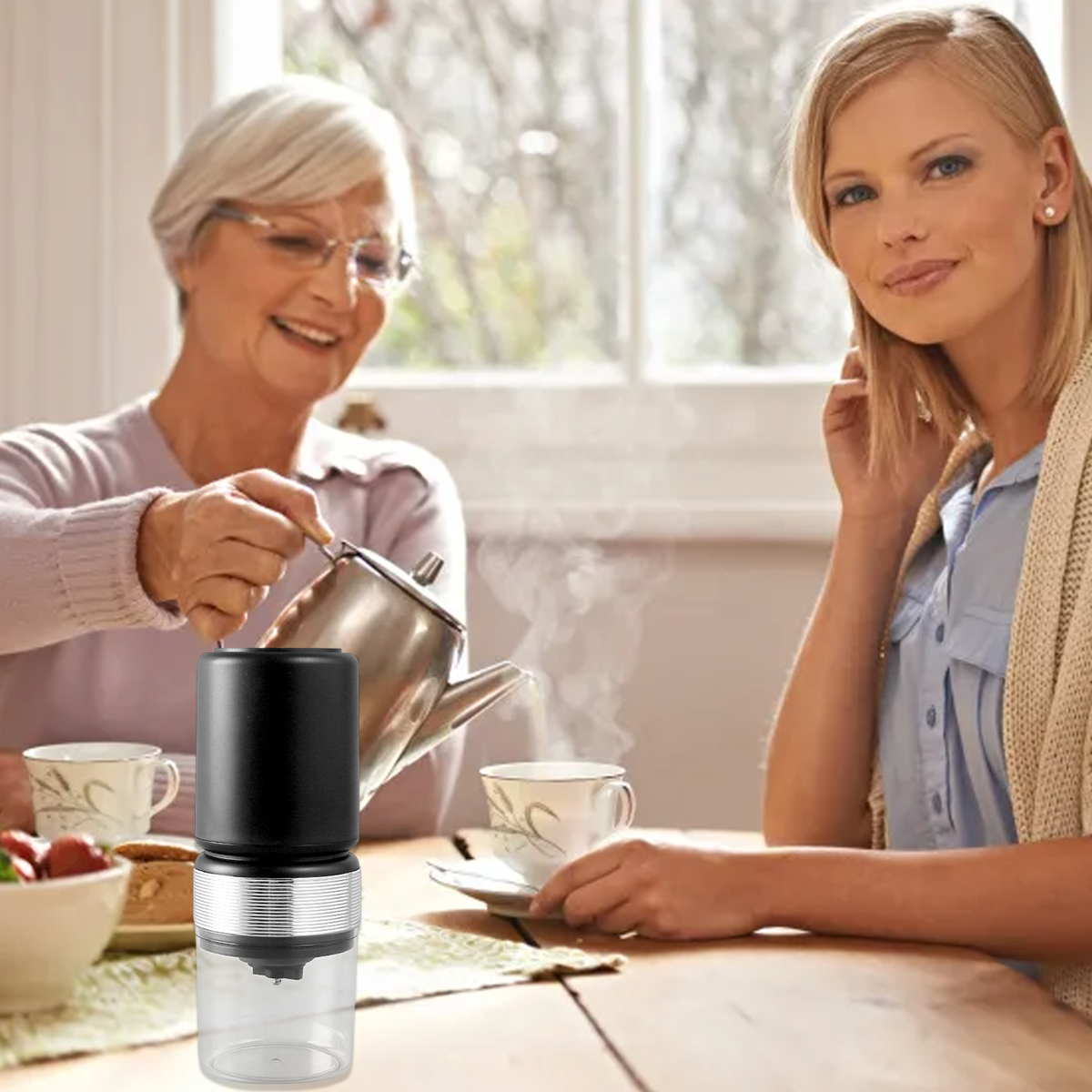Zwei Frauen am Tisch mit Kaffee und Kaffeemühle im Bild.