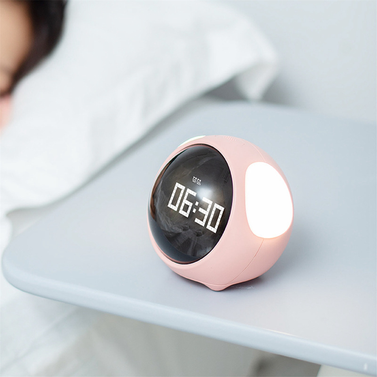 Ein rosa, runder digitaler Wecker mit schwarzem Display, das 06:30 anzeigt, und einem Licht an der Seite.