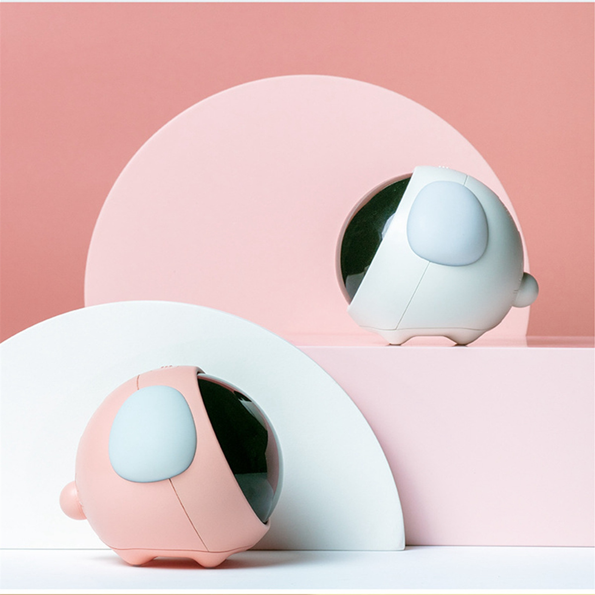 Zwei kleine weiße und rosa dekorative Kugeln auf rosa und weißem Hintergrund.
