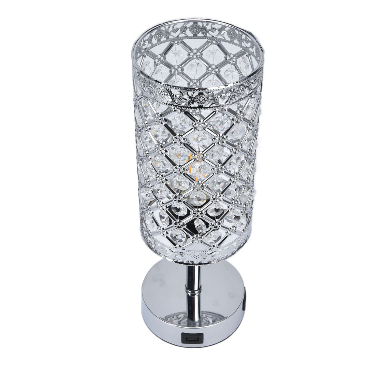 Silberne und Kristall-Tischlampe auf weißer Oberfläche. Die Lampe hat eine zylindrische Form und eine verzierte Oberseite.