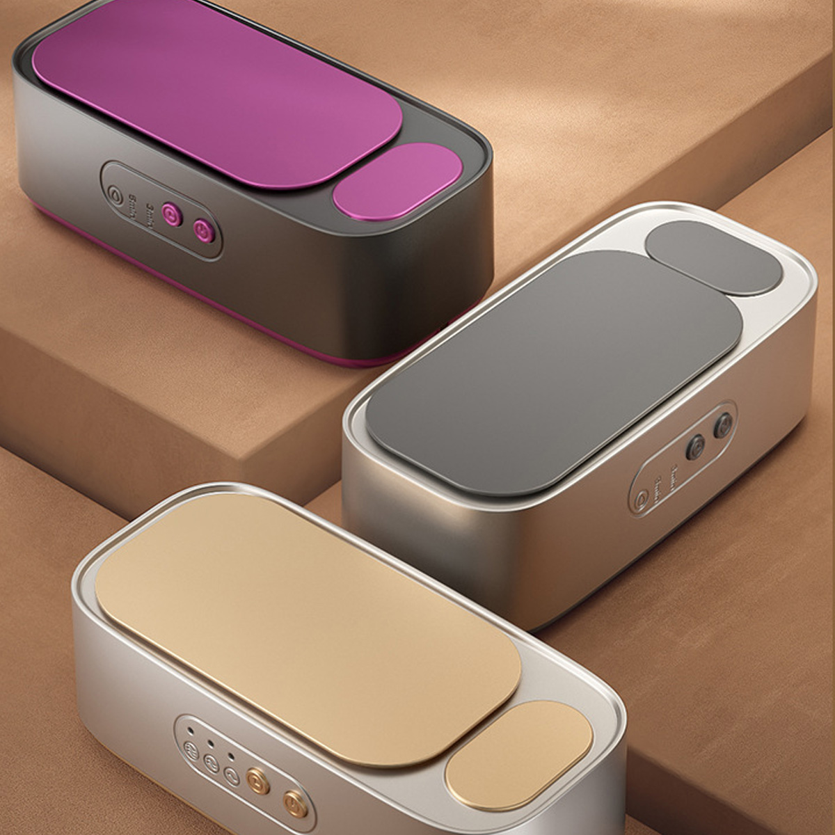 Drei Massagegeräte in Silber, Gold und Lila.