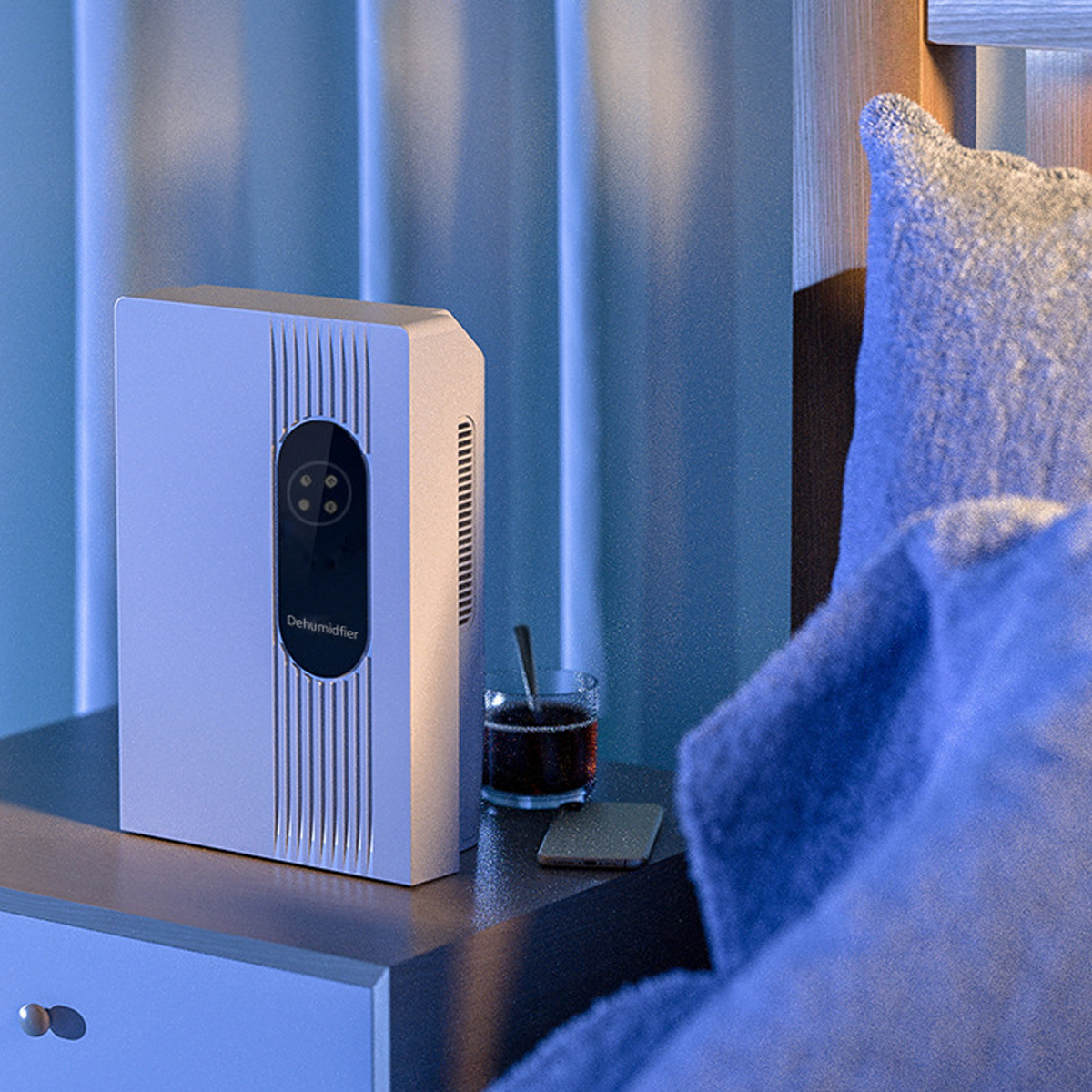 Biały osuszacz na stoliku nocnym. Obok stoi szklanka z napojem i telefon.