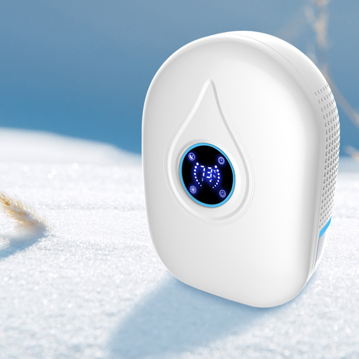 Biały osuszacz z wyświetlaczem i otworami wentylacyjnymi, umieszczony na śniegu. Niebieskie niebo w tle.