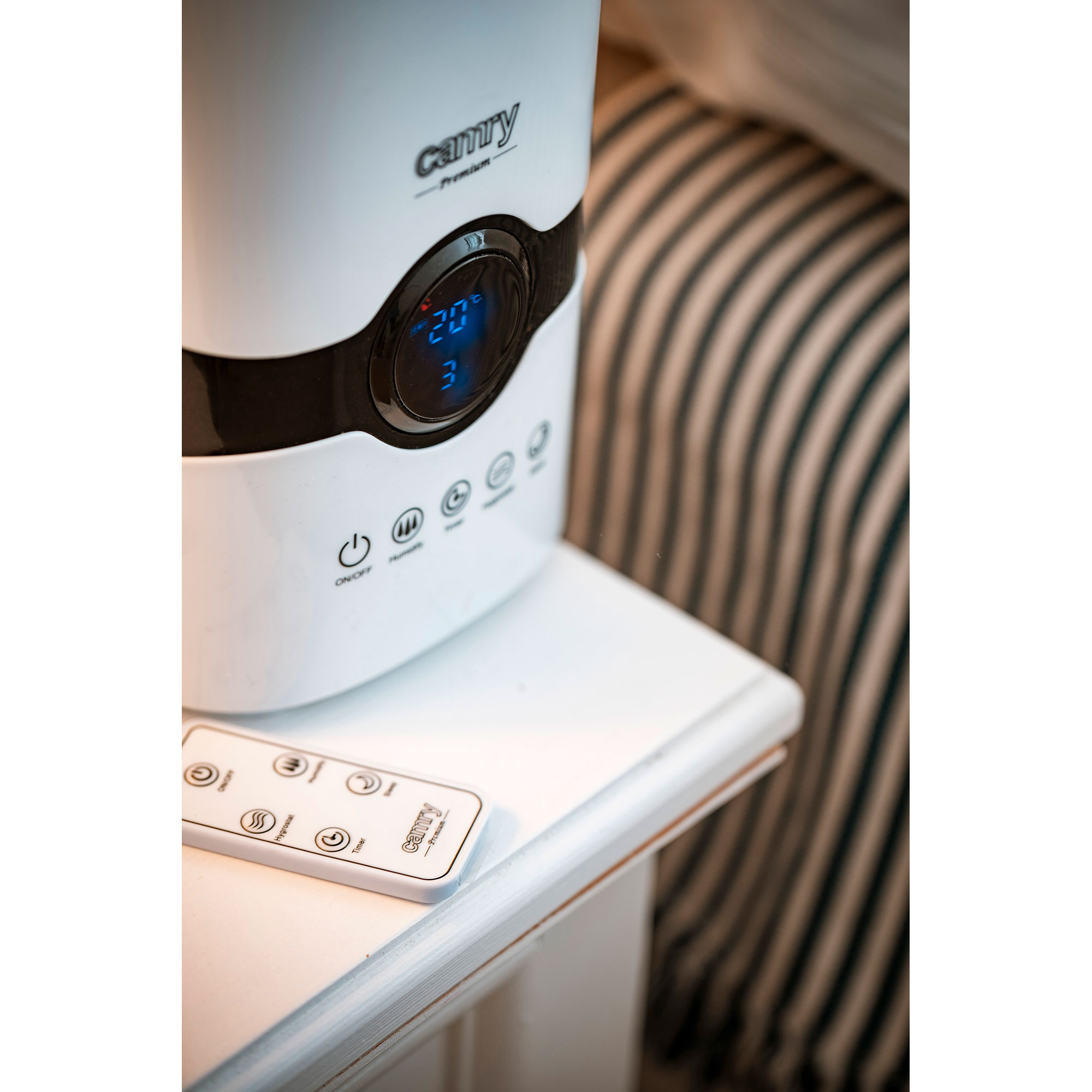 Biały nawilżacz z cyfrowym wyświetlaczem i pilotem na białym stole.