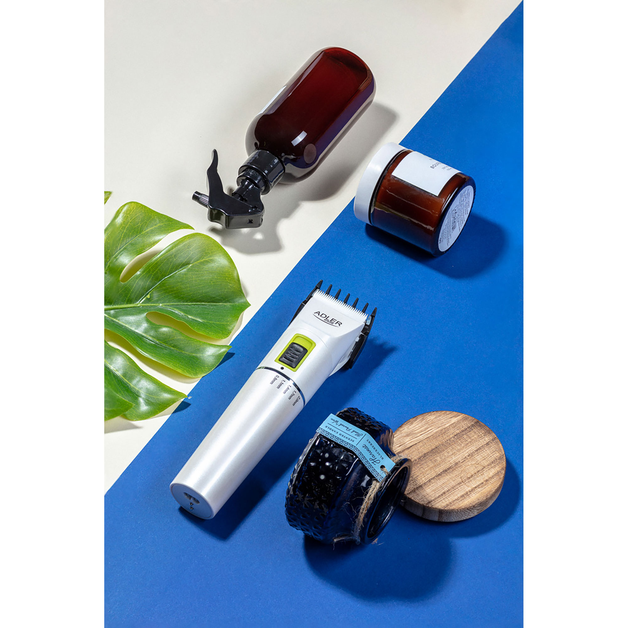 Friseursachen auf blau-weißer Oberfläche. Enthält eine Sprühflasche, Trimmer und Glas.