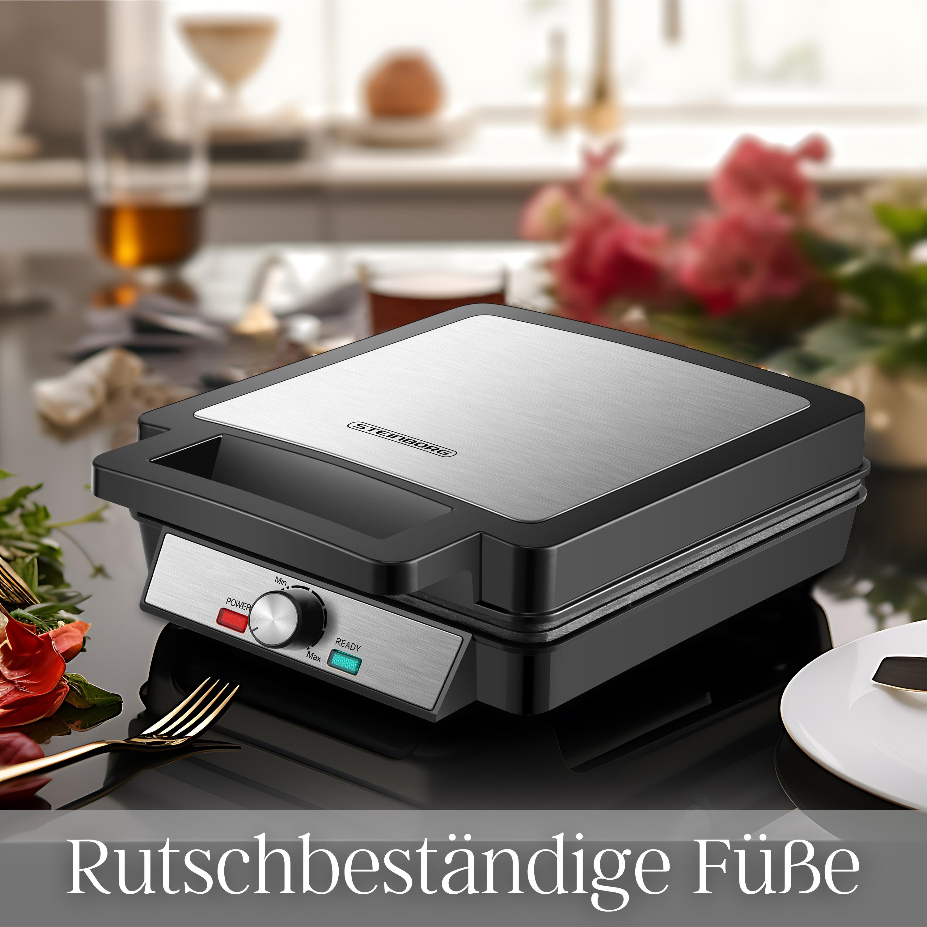 Schwarzer und silberner Waffeleisen auf dunkler Oberfläche, umgeben von Blumen.