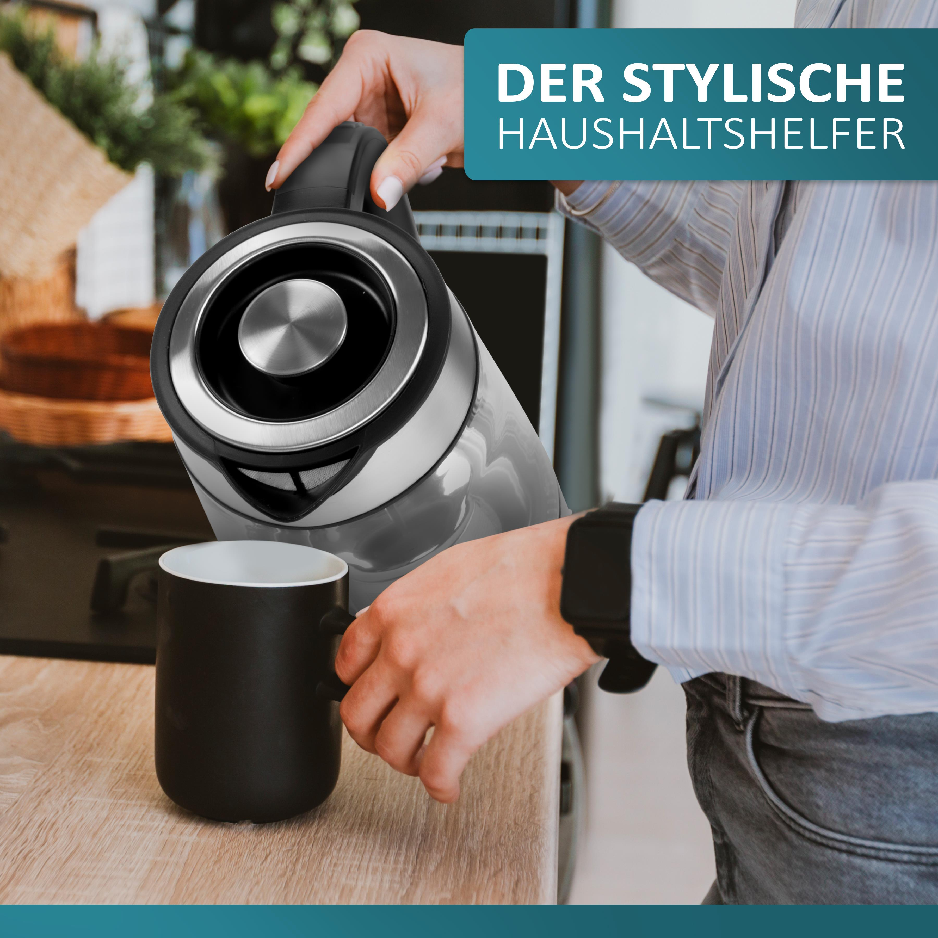 Eine Frau gießt Wasser aus einem Glaskessel in eine schwarze Tasse auf Holz.
