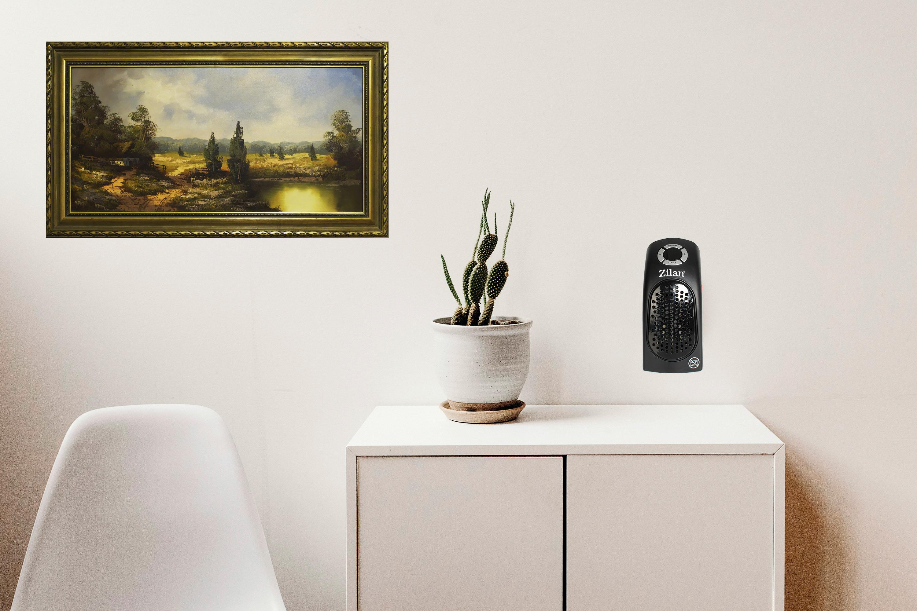 Ein gerahmtes Gemälde an einer Wand, ein Kaktus in einem Topf und ein kleiner Heizlüfter auf einem weißen Schrank.