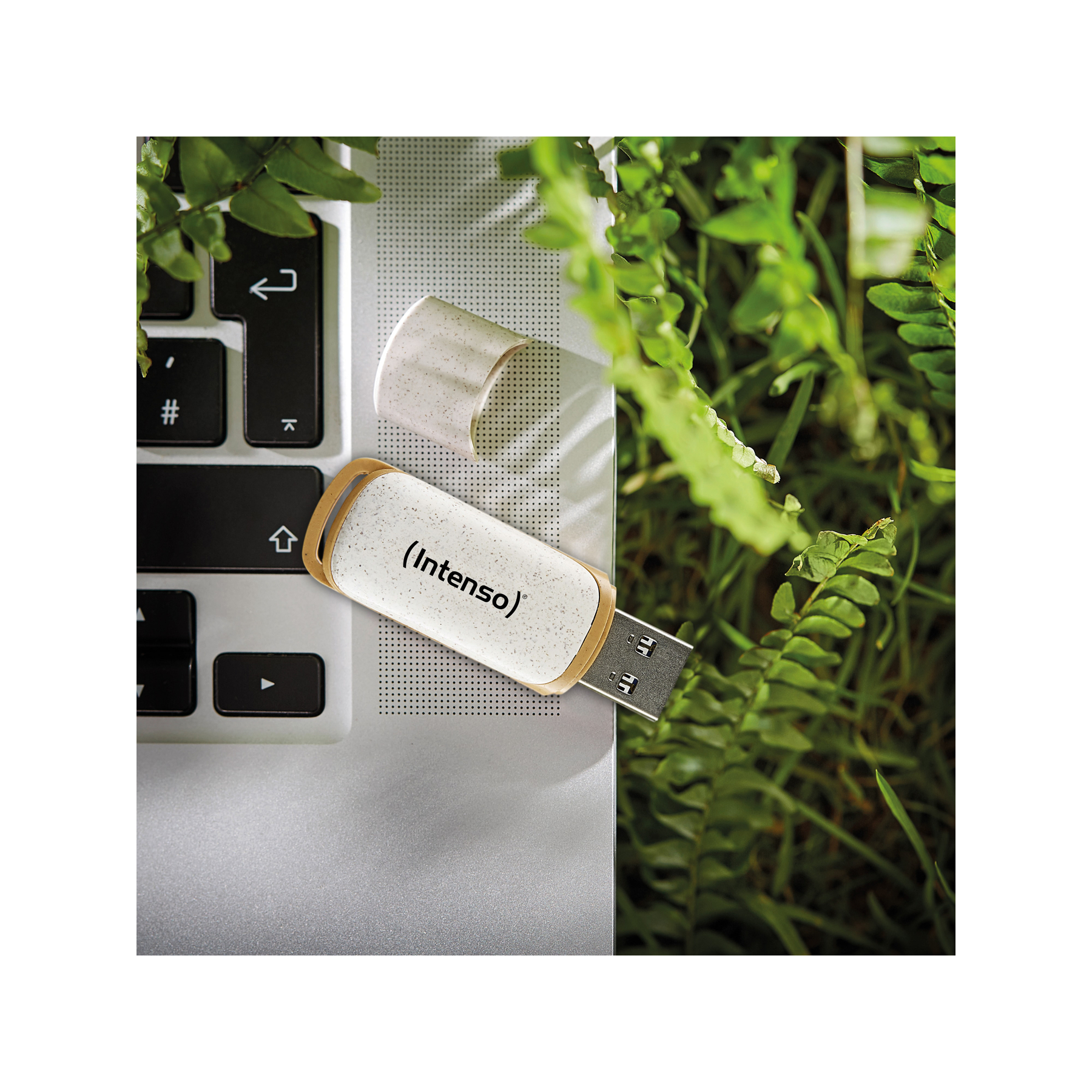 Ein weiß-beiger USB-Stick liegt auf einer Laptop-Tastatur. Es hat ein Metallende und eine Kappe.