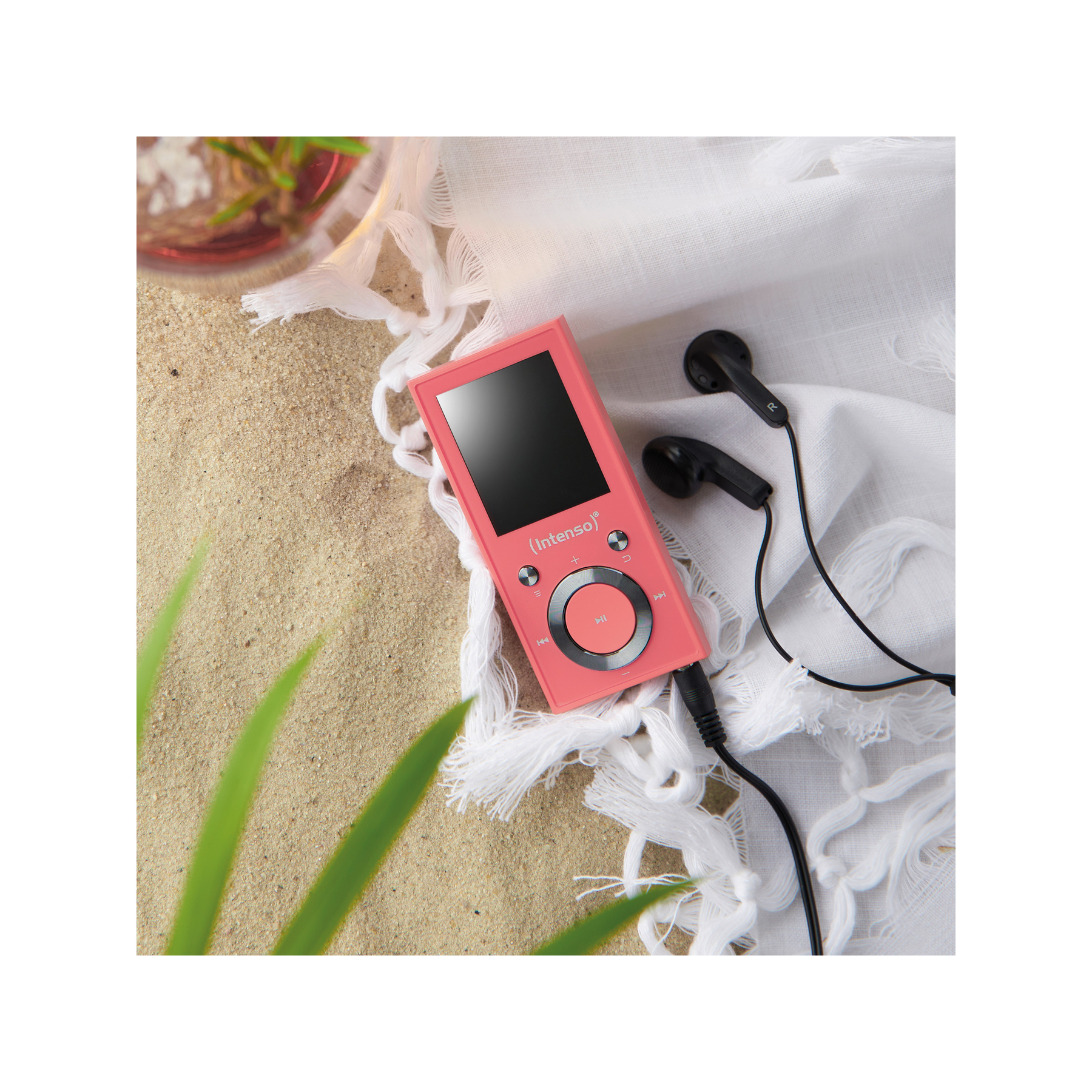 Rosa MP3-Player mit schwarzen Kopfhörern auf einem sandigen Strand.