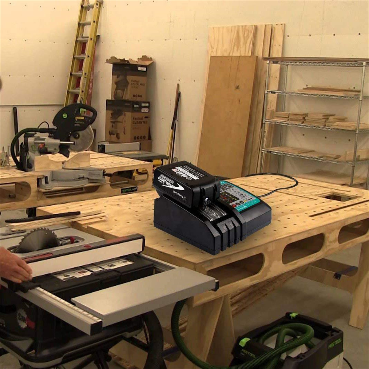 Eine Werkstattszene mit einem Batterieladegerät auf einem Holztisch. Werkzeuge und Holzbretter sind sichtbar.