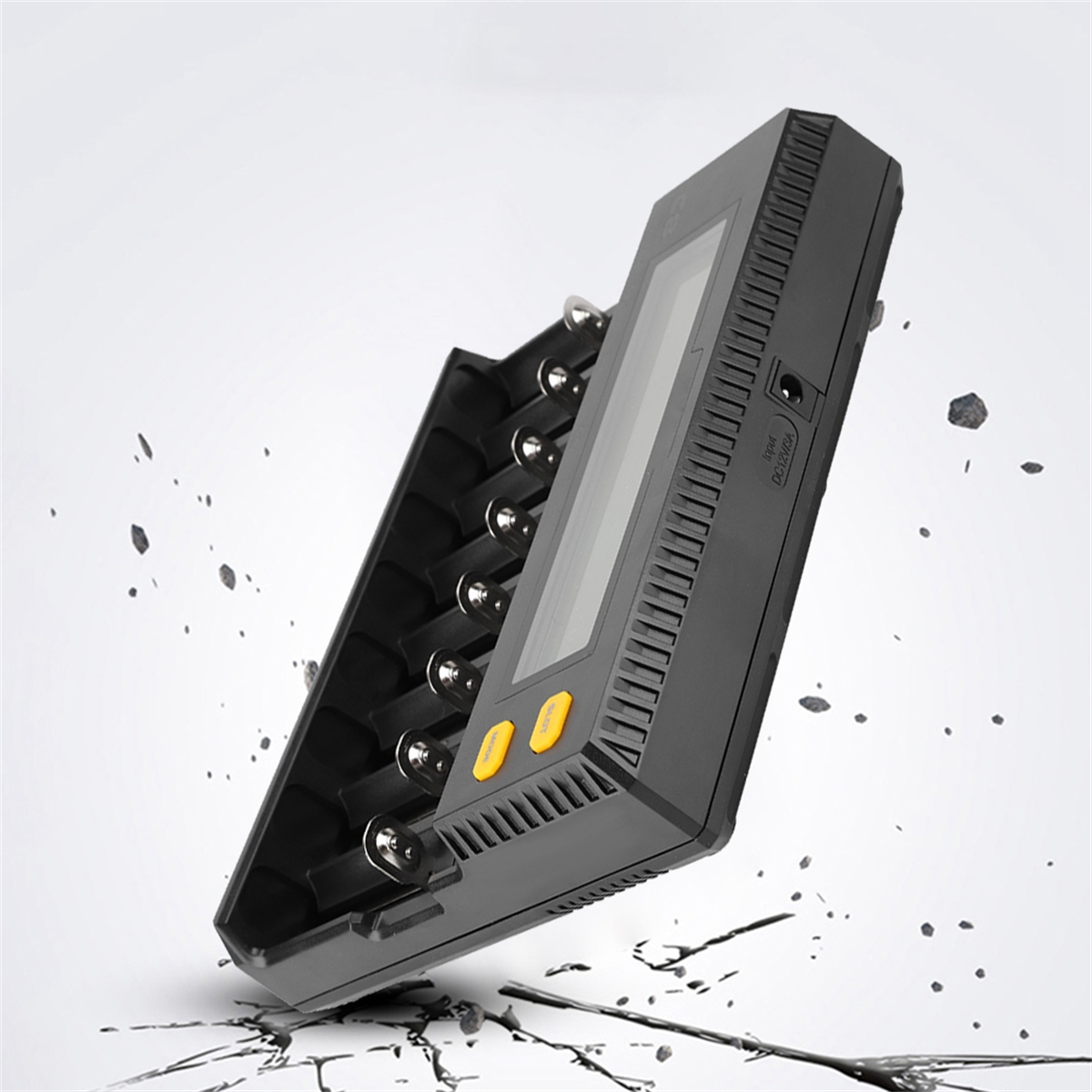 Ein schwarzes Batterieladegerät mit Bildschirm und zwei gelben Knöpfen. Es liegt auf einer zerbrochenen Oberfläche.