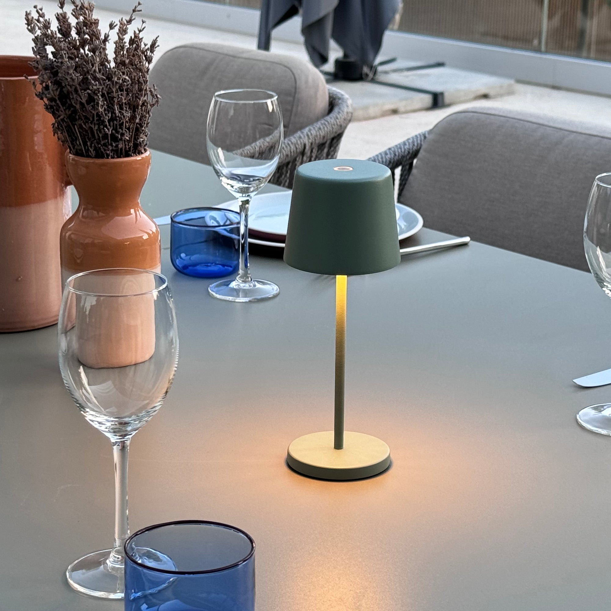 Grüne Lampe auf einem Tisch mit Gläsern und einer Vase. Umgebungslicht.