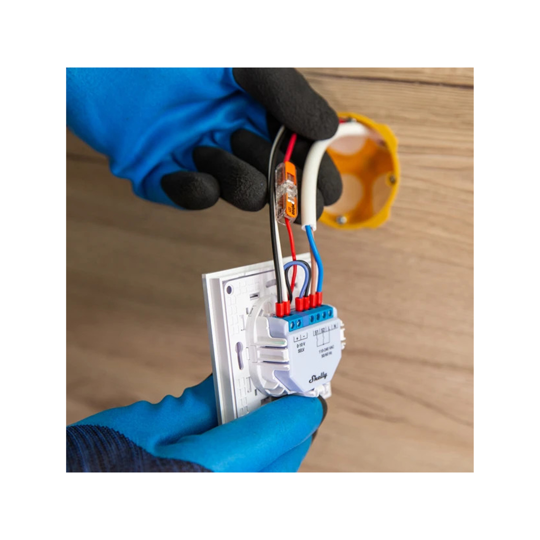Manos con guantes azules conectando cables a un componente eléctrico blanco.