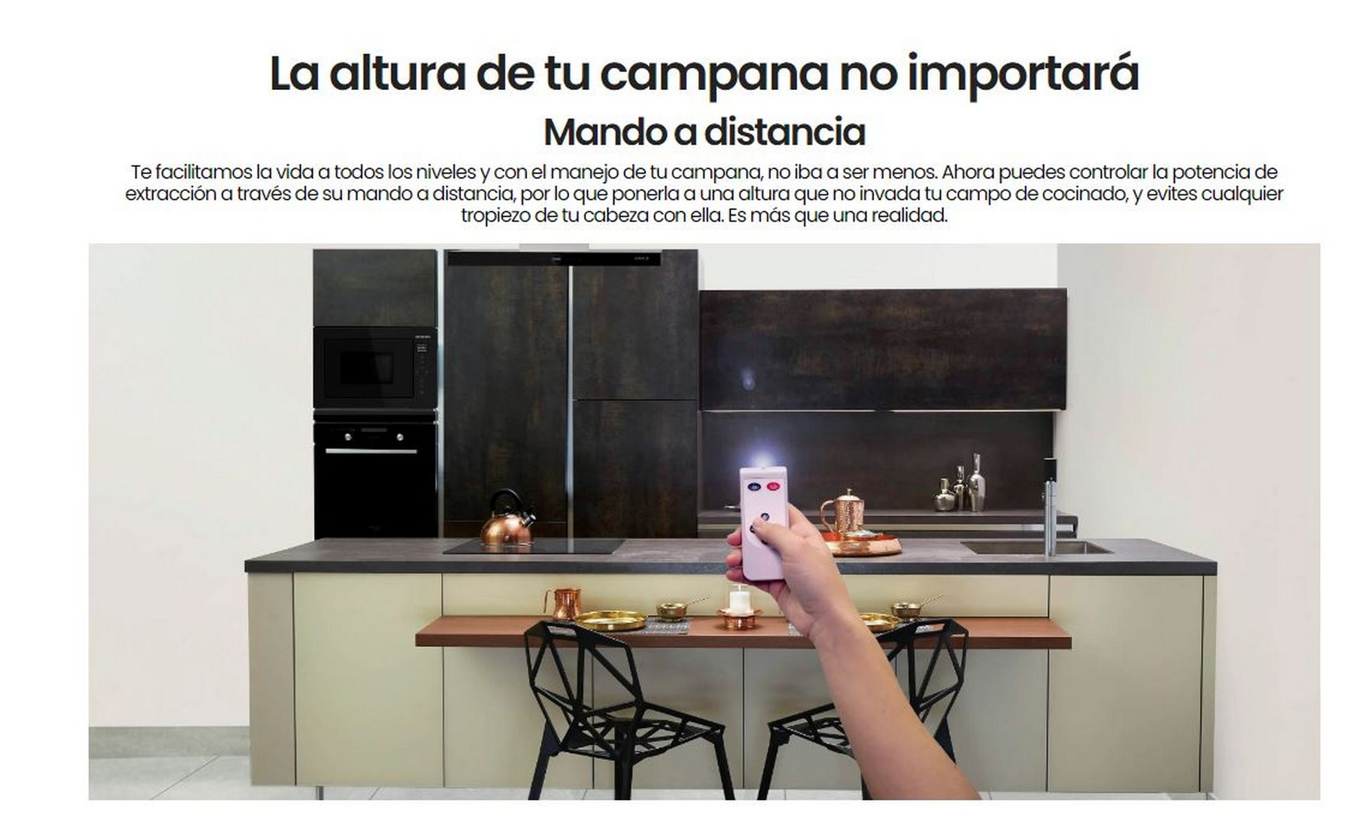 Cocina con gabinetes, persona sosteniendo un control remoto y campana extractora de acero inoxidable.