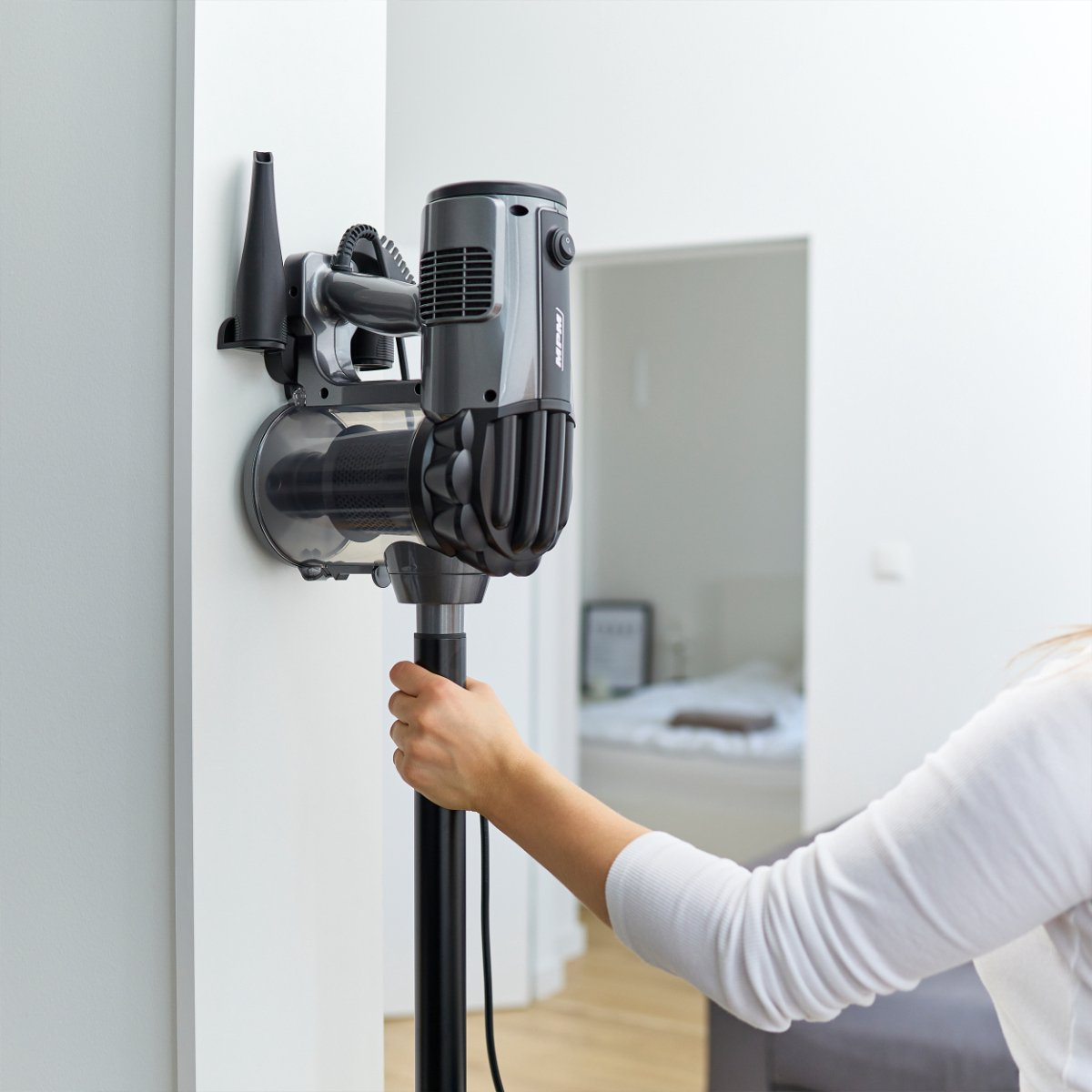 Eine Person, die einen an der Wand montierten Staubsauger hält.
