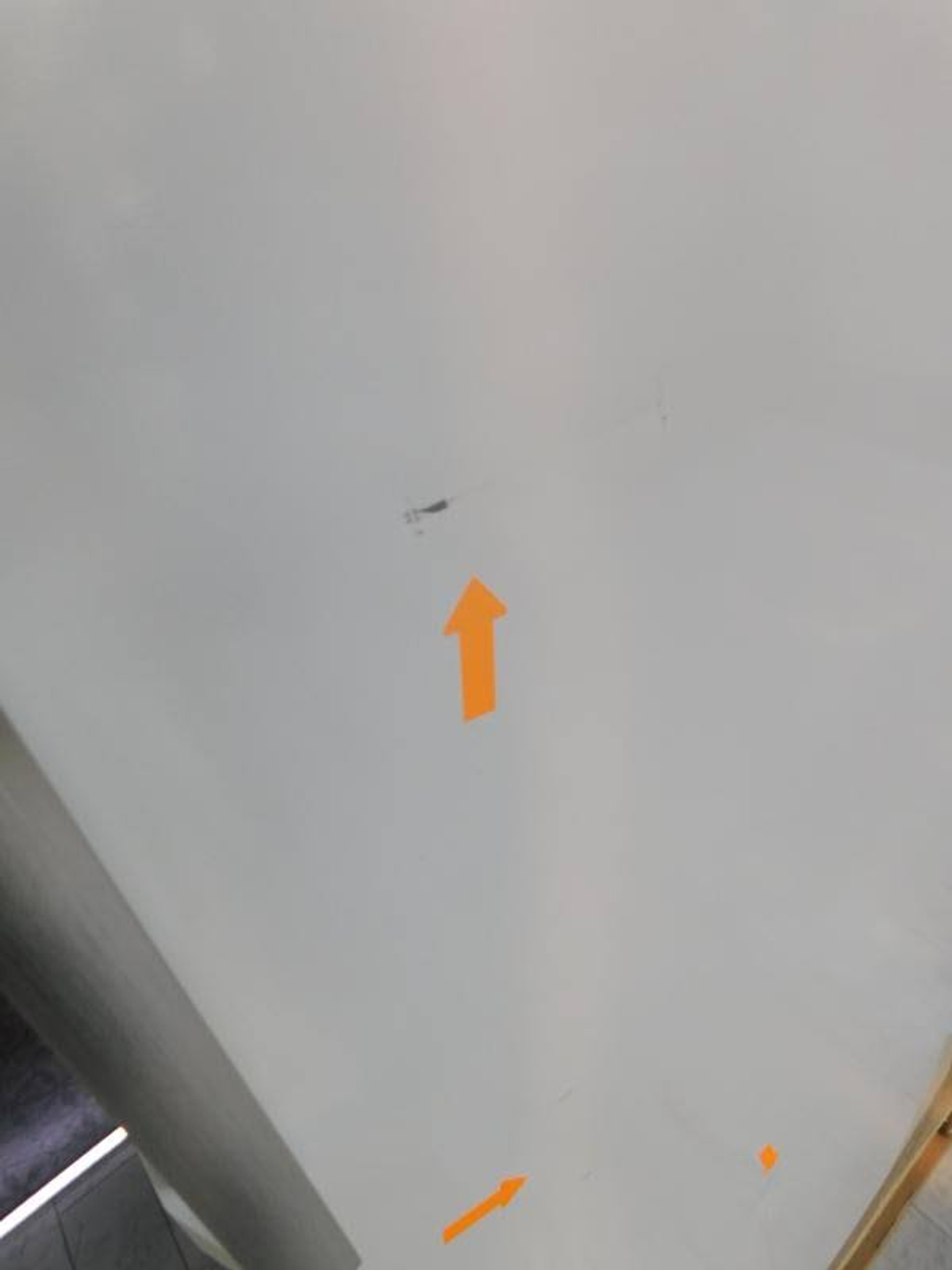 Biała powierzchnia z pomarańczowymi strzałkami skierowanymi w górę i w prawo. Widoczne ciemne znaki.