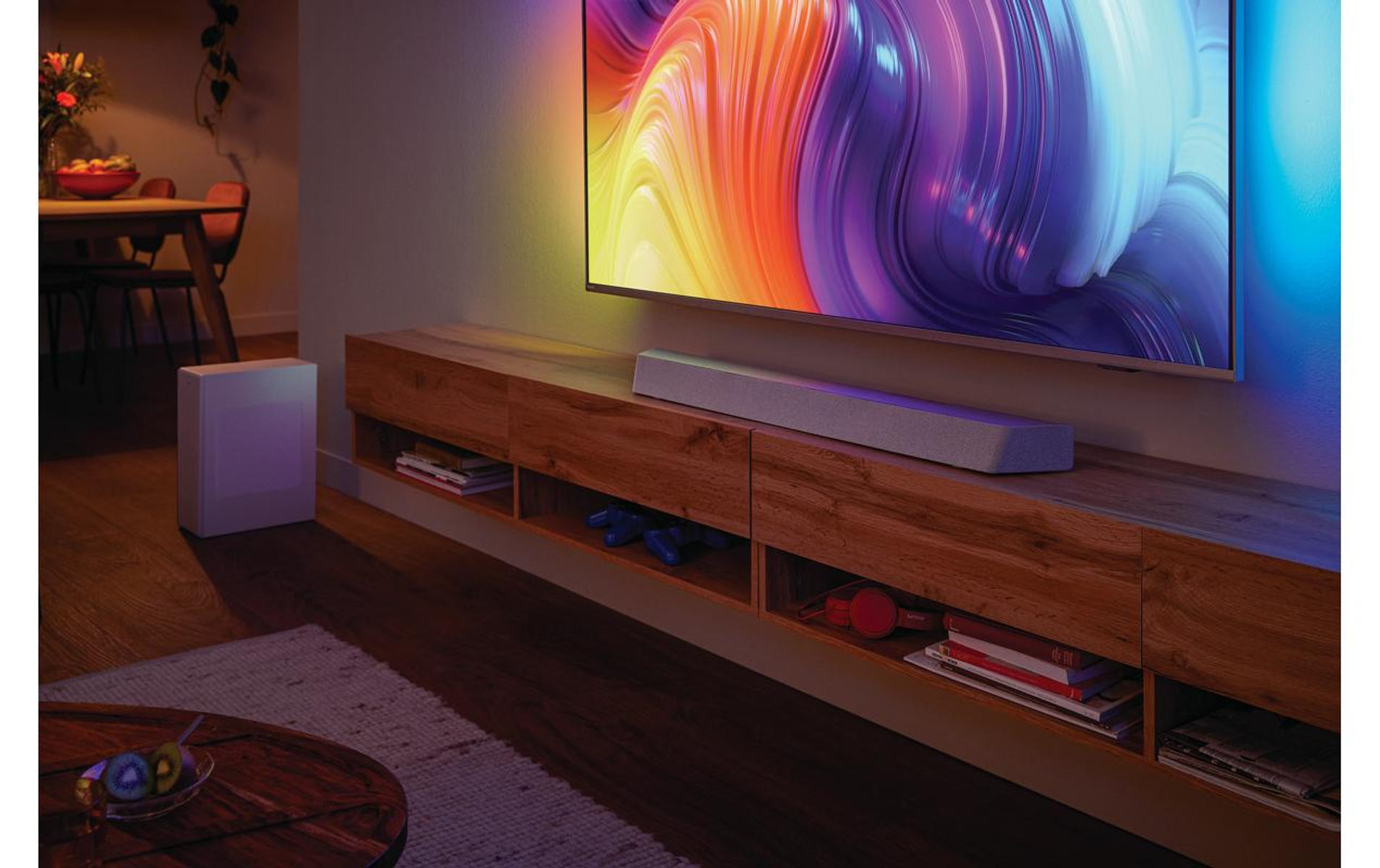 Wohnzimmerszene mit Fernseher, Soundbar und Subwoofer. Holzmöbel. Warme Beleuchtung.