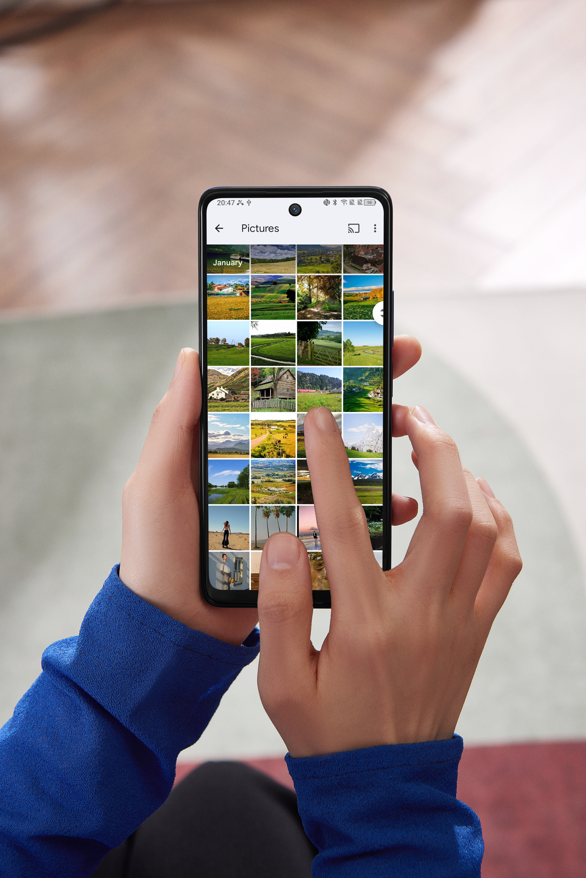 Una persona sosteniendo un teléfono inteligente que muestra una galería de fotos con escenas al aire libre.