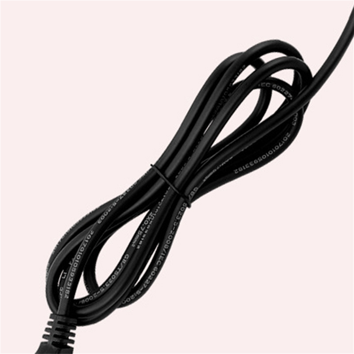 Schwarzes Kabel aufgerollt mit einem schwarzen Kabelbinder. Beigefarbener Hintergrund.
