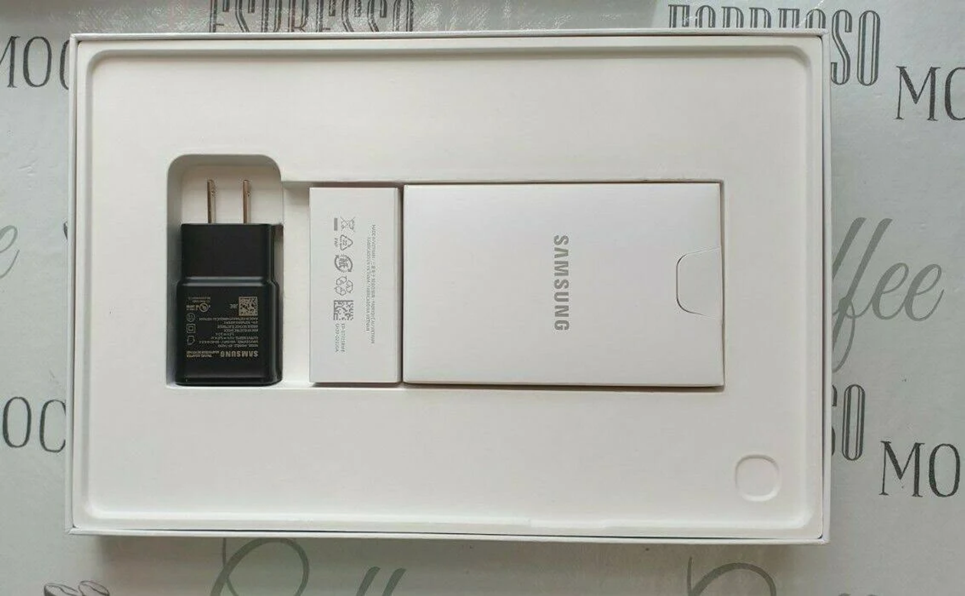 Tabletzubehör in einer weißen Box: Ladegerät, kleine weiße Box und eine größere weiße Box mit Samsung-Logo.