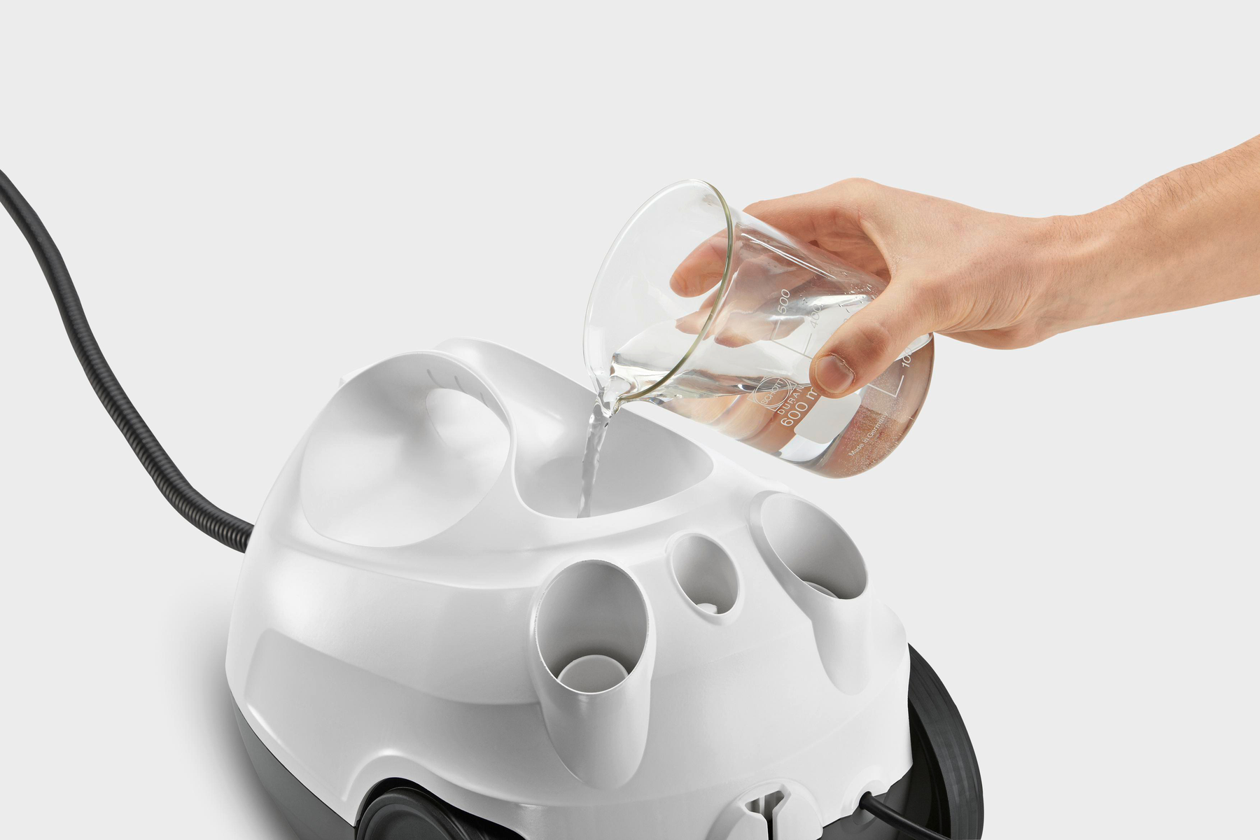 Osoba wlewa wodę ze zlewki do białego urządzenia do czyszczenia parą, na białym tle.