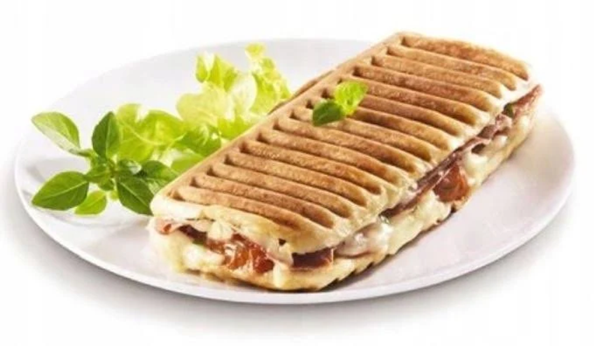 Kanapka panini na białym talerzu z dodatkiem sałaty. Kanapka jest grillowana.