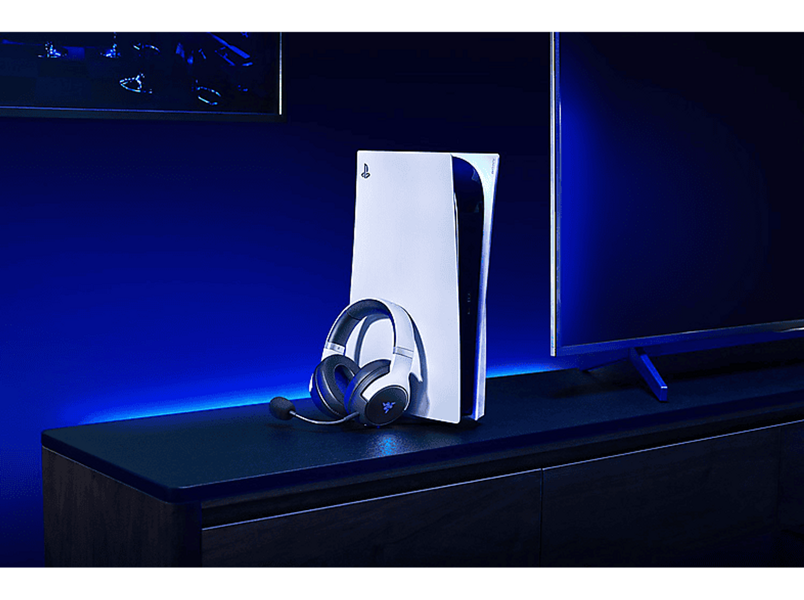 Eine weiße Playstation 5 Konsole mit Headset. Die Szene ist in einem dunklen Raum mit blauer Beleuchtung auf einer schwarzen Oberfläche.