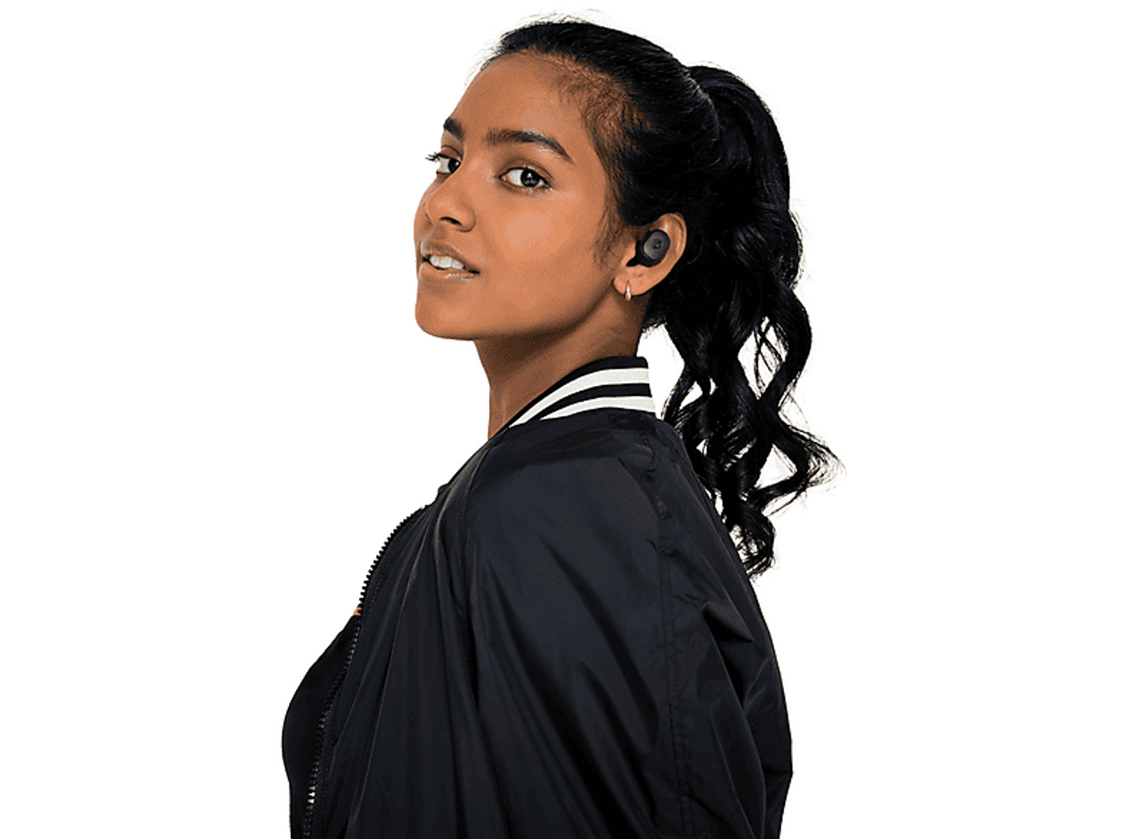 Woman with dark hair wearing earbuds, looking to the right with a black jacket on. White background.