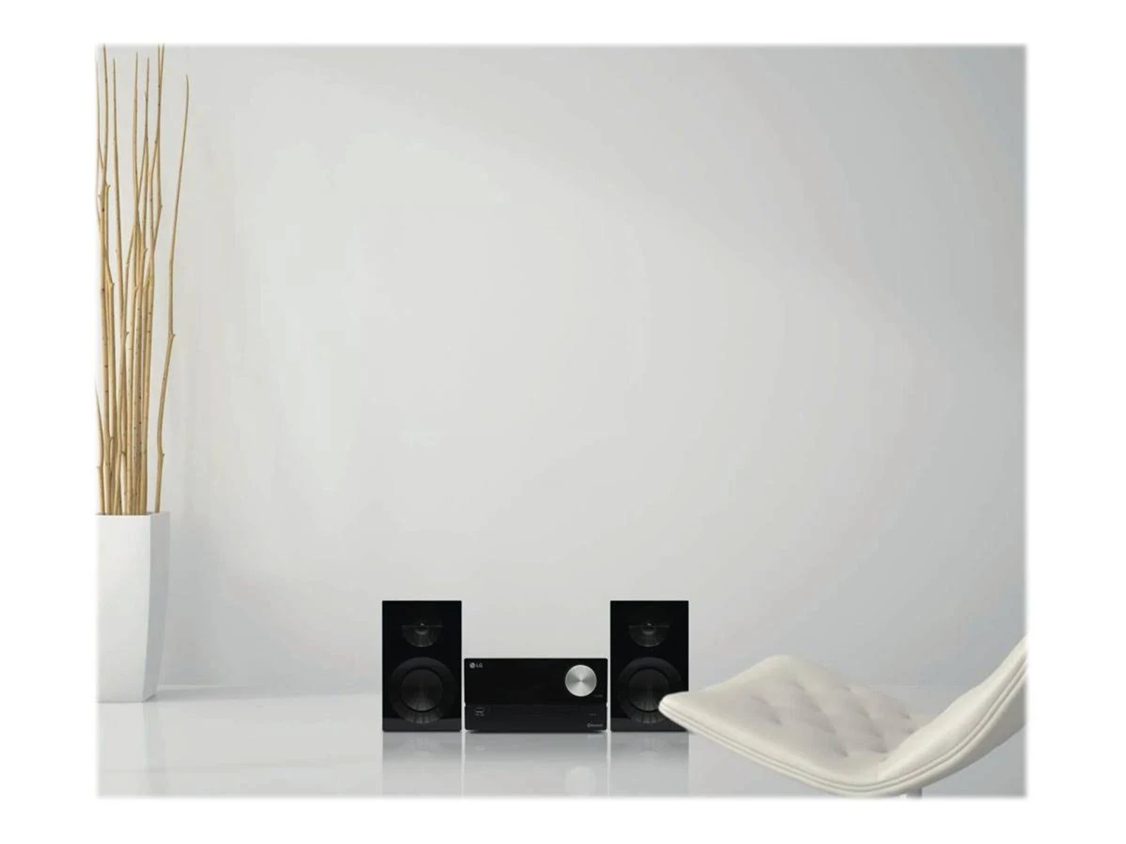 Salón moderno con altavoces, receptor y silla blanca. Pared y suelo blancos.