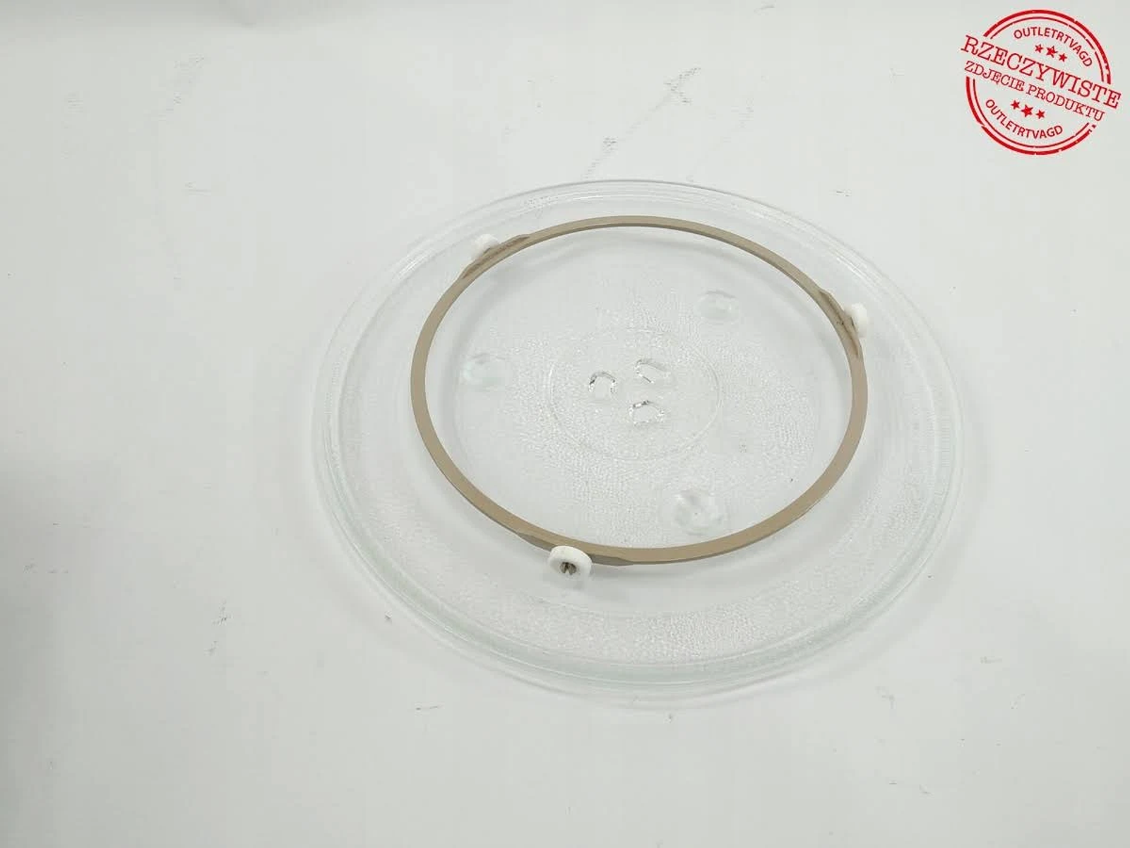 Ein klarer Mikrowellenteller mit braunem Ring in der Mitte, auf weißer Oberfläche.