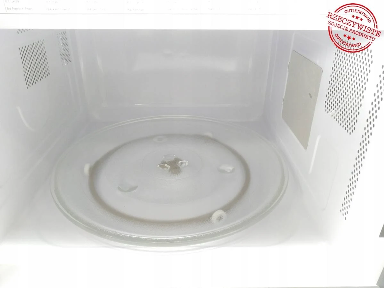 Innenraum eines Mikrowellenherdes mit Glasplatte und rotem Outlet-Schild.