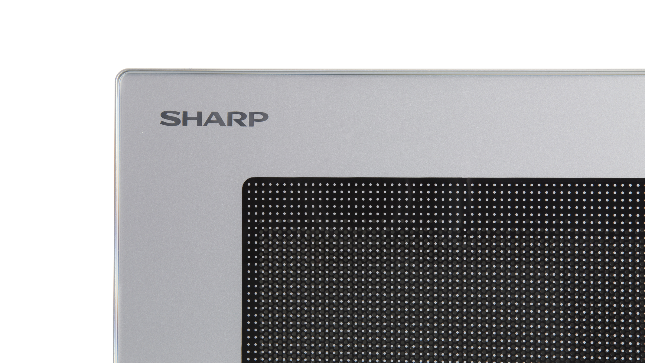 Zbliżenie srebrnej kuchenki mikrofalowej. Nazwa marki SHARP znajduje się nad czarną kratką.