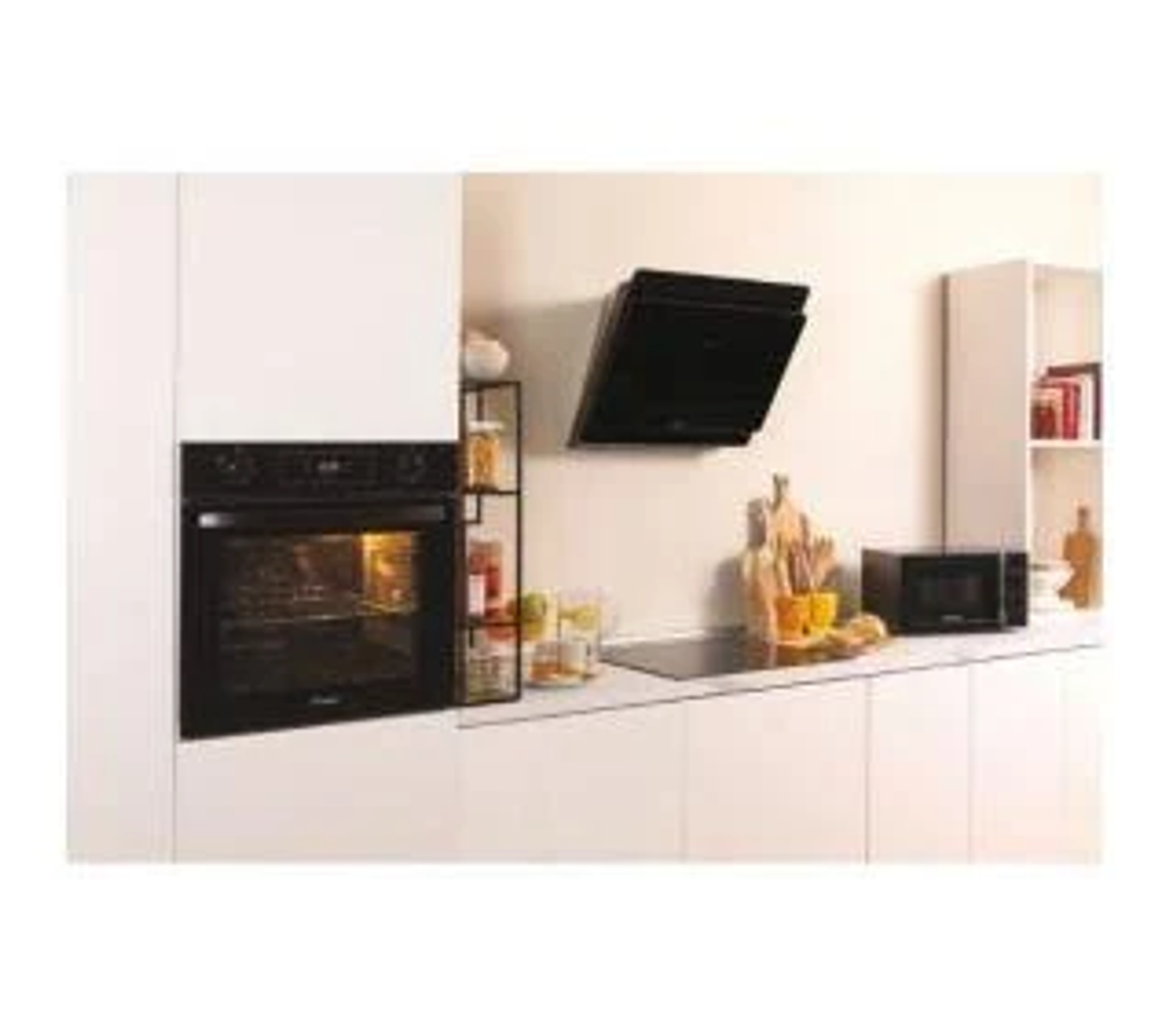 Escena de cocina con horno empotrado, encimera, microondas y campana. Armarios y encimera blancos.