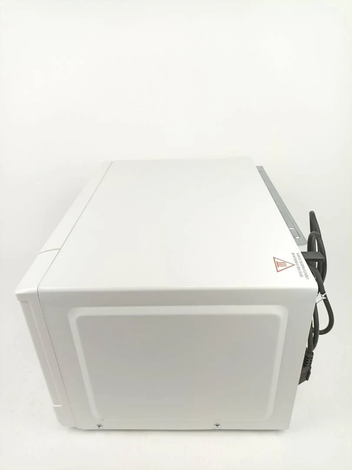 Un horno microondas blanco, vista superior, con un cable y una etiqueta de advertencia.